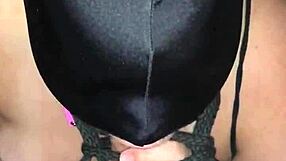 Masked figure bound tightly while performing deep blowjob on hard cock.